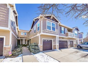 Tan two-story townhome with attached garage and snow-covered walkway at 17359 Waterhouse Cir # C, Parker, CO 80134