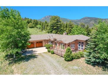 Charming ranch-style home with a large deck, wooden garage doors, and mountain views at 153 Gold Run Trl, Idaho Springs, CO 80452