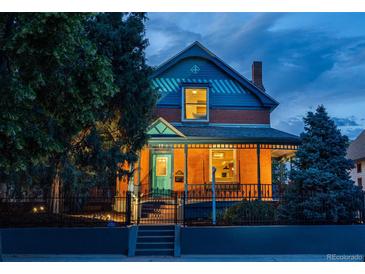 Charming two-story brick home with a covered front porch, black iron fence and inviting curb appeal at twilight at 2445 W 39Th Ave, Denver, CO 80211