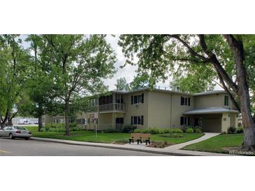 Two-story tan apartment building featuring a grassy lawn, bench and several large leafy trees at 755 S Clinton St # 1B, Denver, CO 80247