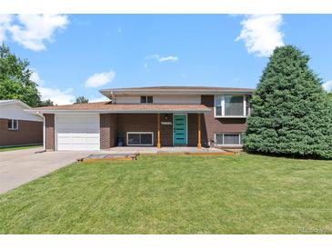 Charming brick home with well-manicured lawn, a blue door, and attached garage at 8333 Depew Way, Arvada, CO 80003