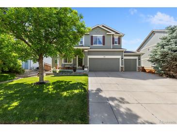Charming two-story home features a three car garage, lush lawn, and a mature shade tree at 139 N Prairie Falcon Pkwy, Brighton, CO 80601