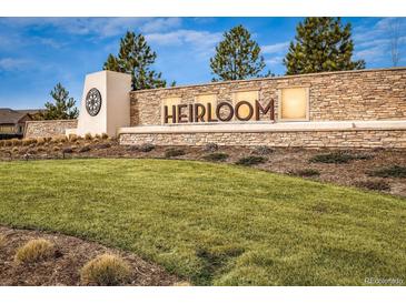 Stone monument sign for Heirloom community surrounded by a well manicured lawn and professional landscaping at 14589 Hagus Pl, Parker, CO 80134