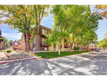 Inviting exterior of brick apartments nestled among mature trees and a well-maintained lawn at 7755 E Quincy Ave # 104A1, Denver, CO 80237