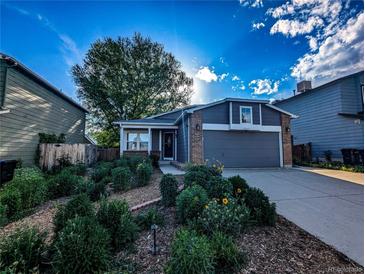 Inviting home featuring a charming front yard with mature landscaping and a two-car garage at 6365 Xavier Ct, Arvada, CO 80003