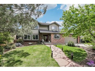 Charming two-story home with a well-manicured lawn, mature trees, and a stone pathway leading to the entrance at 8291 S Krameria Way, Centennial, CO 80112