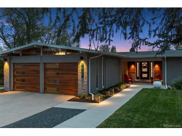 Modern home featuring a wooden garage door, a well-lit walkway, and a professionally landscaped front yard at 7065 E Caley Ave, Centennial, CO 80111