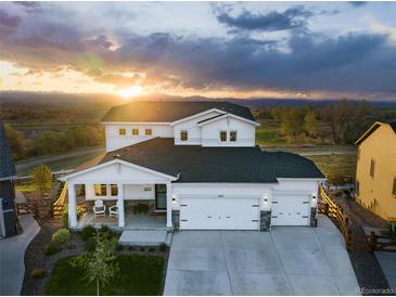 Beautiful two-story home with white siding and a three-car garage, showcasing a lovely sunset view at 1601 Mariah Ln, Erie, CO 80516