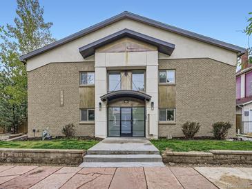 Two-story apartment building with brick and stucco, featuring a covered entrance and manicured landscaping at 2460 W Caithness Pl # 105, Denver, CO 80211