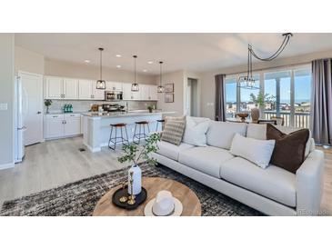 Open-concept living room with modern light fixtures and a spacious kitchen with a large island at 711 N Waterloo Ct, Aurora, CO 80018