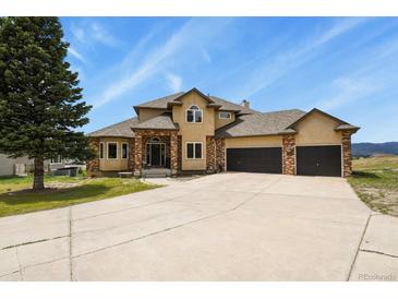 Inviting home with brick accents, three-car garage, and ample driveway space on a well-manicured lawn at 937 Caribou Dr, Monument, CO 80132