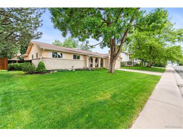Charming single-story home with a lush, green front lawn and mature shade trees at 7442 S Wellington St, Centennial, CO 80122