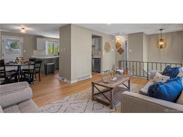 Inviting living room seamlessly connects to the kitchen with modern decor and hardwood floors, bathed in natural light at 9598 Lou Dr, Northglenn, CO 80260