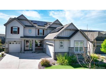 Attractive, light grey two-story home with stone accents, solar panels, three-car garage and professional landscaping at 8867 S Zante St, Aurora, CO 80016