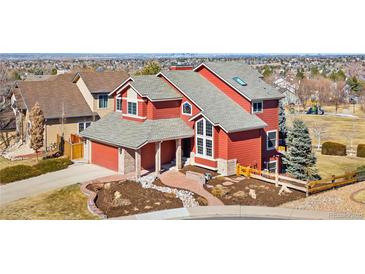 Inviting red two-story home featuring a well-manicured front yard and an attached two-car garage at 1621 Beacon Hill Dr, Highlands Ranch, CO 80126