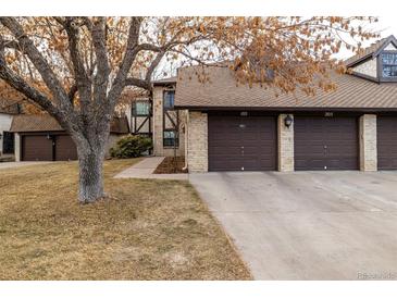 Townhome exterior with individual garages, brick facade, and a mature tree in the front yard at 7250 Eastmoor Dr # 105, Denver, CO 80237