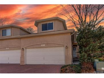 Charming townhome featuring a two-car garage and beautiful landscaping under a vibrant sunset sky at 12388 E Caspian Dr, Aurora, CO 80014