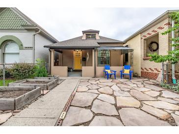 Charming bungalow with a bright yellow door, stone patio, and lovely landscaping at 30 Fox St, Denver, CO 80223