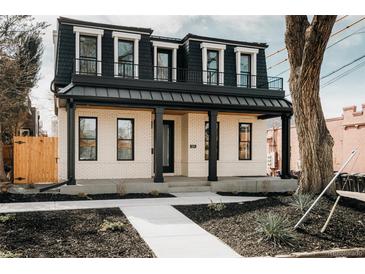 Charming two-story home with a black metal roof, covered porch, and landscaped front yard at 1016 28Th St, Denver, CO 80205