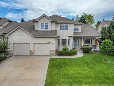 Inviting home with a well-manicured lawn, three-car garage and a charming covered porch, perfect for relaxing outdoors at 14878 E Aberdeen Ave, Centennial, CO 80016