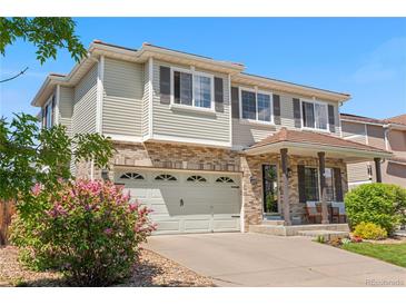 Charming two-story home featuring a brick facade, well-maintained lawn, and attached two-car garage at 15353 E 98Th Pl, Commerce City, CO 80022