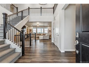 Grand foyer featuring a staircase with iron railings, dark wood floors, and an open view to the living room at 6679 Kenzie Cir, Castle Pines, CO 80108