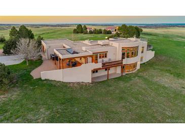 Stunning exterior elevation showcases a modern stucco home with a deck, hot tub, and scenic views in the countryside at 1764 Mesa Ridge Ln, Castle Rock, CO 80108