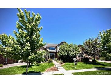 Charming two-story home featuring a lush front yard, mature trees, and manicured landscaping at 15857 E Aberdeen Ave, Centennial, CO 80016