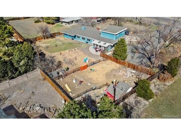 Sprawling property featuring a spacious yard with play structures and a fenced area for pets or gardening at 7400 W Quincy Ave, Littleton, CO 80123