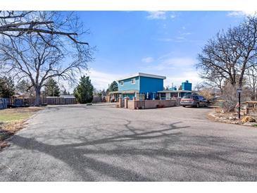Bright blue two-story home featuring a spacious parking area and unique architectural details at 7400 W Quincy Ave, Littleton, CO 80123
