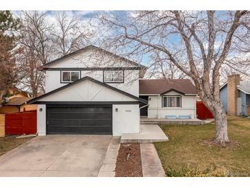 Charming two-story home featuring a black garage door and painted white brick at 6426 Zang Ct, Arvada, CO 80004