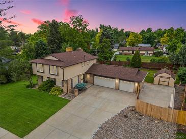Two-story home boasts a spacious driveway, charming shed, lush lawn, and an attached two-car garage at 5954 W Leawood Dr, Littleton, CO 80123