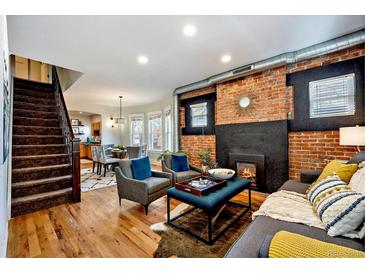 Inviting living room with a cozy fireplace, exposed brick, and hardwood floors, creating a warm and stylish atmosphere at 3233 W 29Th Ave, Denver, CO 80211