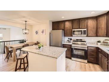 Well-lit kitchen features stainless steel appliances, granite countertops, and dark cabinetry with a center island at 3578 Tranquility Trl, Castle Rock, CO 80109