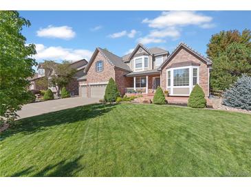 Beautiful two-story brick home with a well-manicured lawn and attached two car garage at 6987 Esperanza Dr, Castle Pines, CO 80108