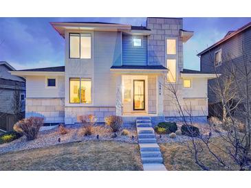Modern home featuring a stone facade, large windows, landscaped front yard, and welcoming front entrance at 15818 W 95Th Ave, Arvada, CO 80007