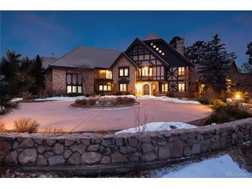 Stunning Tudor-style home with a circular driveway and beautiful stone accents at twilight at 7225 Box Canyon Rd, Sedalia, CO 80135