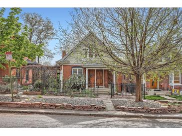 Charming brick home featuring a wrought iron fence and a mature shade tree in the front yard at 3356 Quivas St, Denver, CO 80211