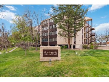 Morningside Condominiums exterior view shows building behind stone sign on green lawn at 3470 S Poplar St # 102, Denver, CO 80224