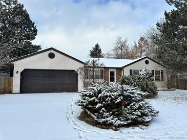 Ranch-style home with attached garage, snow-covered lawn, and mature shrubs at 17422 E Progress Dr, Centennial, CO 80015