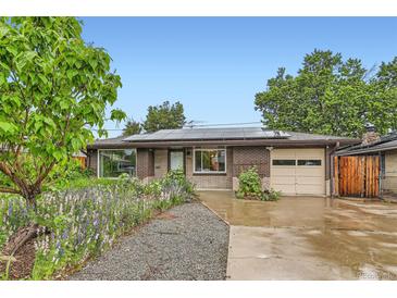 Charming brick home featuring solar panels, a well-kept yard, and an attached one-car garage at 6051 Ivanhoe St, Commerce City, CO 80022