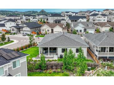 View of a well-maintained gray home, surrounded by lush greenery and a vibrant neighborhood with mountain views in the background at 1465 Gentle Rain Dr, Castle Rock, CO 80109