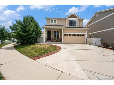 Two-story tan home featuring a two-car garage, manicured lawn, and inviting front entrance at 5572 Killarney St, Denver, CO 80249