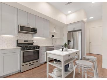 Bright kitchen features stainless steel appliances, light grey cabinetry, and a stylish kitchen island at 2876 W 53Rd Ave # 122, Denver, CO 80221