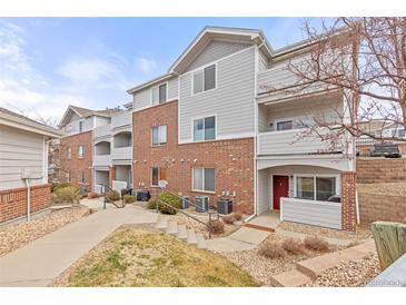 Brick and gray-sided condo with a red front door, small porch and landscaped yard at 5537 Lewis Ct # 1, Arvada, CO 80002
