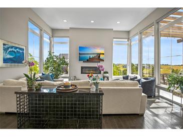 Bright and spacious living room with a fireplace, large windows, and comfortable seating at 8263 Merryvale Trl, Parker, CO 80138