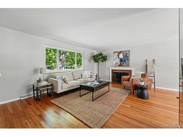 Bright living room with hardwood floors, area rug, and brick fireplace at 1905 S Linden Ct, Denver, CO 80224