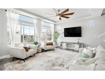 Bright living room with a ceiling fan, large windows, and modern furniture at 18143 E 104Th Way, Commerce City, CO 80022