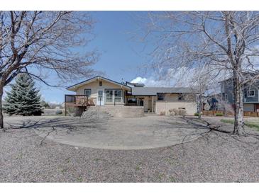 Charming single-Gathering home with a stone patio, wooden deck, and a large circular driveway at 7890 W 43Rd Pl, Wheat Ridge, CO 80033
