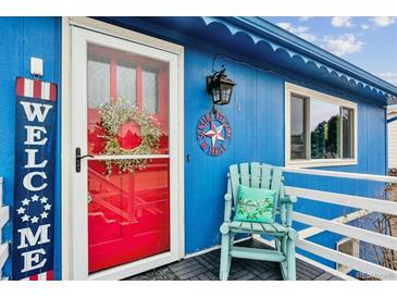 Charming blue home with a welcoming red door and a cozy, decorated front porch with light blue chair at 714 S Tabor St, Elizabeth, CO 80107